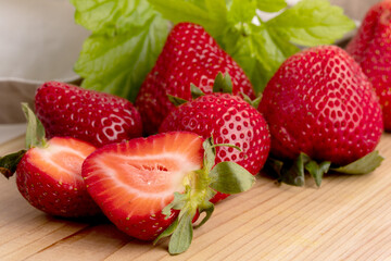 large ripe red strawberries cut up on a wooden board