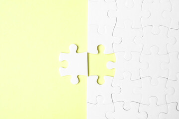 Blank white puzzle with separated piece on yellow background, flat lay