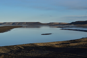Mar sereno al atardecer con colina y cielo azul de fondo