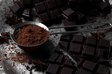 Delicious dark chocolate and cocoa powder on metal plate, closeup