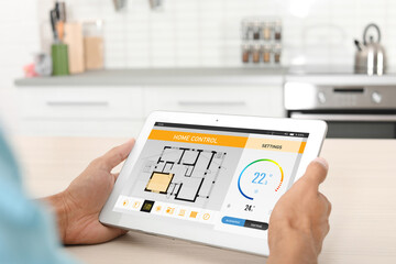 Energy efficiency home control system. Man using tablet to set indoor temperature, closeup