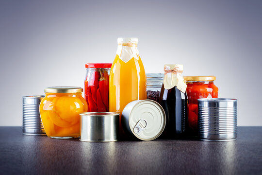 Canned food on the table on gray background. Various canned vegetables, meat, fish and fruits in tin and glass.