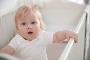 Cute little baby in crib at home