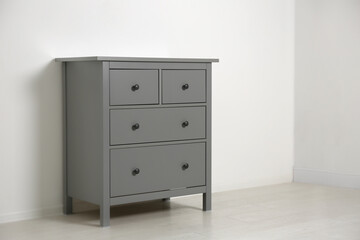 Grey chest of drawers near light wall