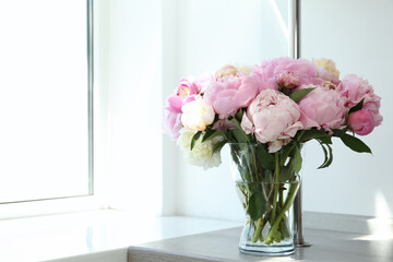 Bouquet of beautiful peonies in vase on wooden table. Space for text