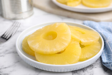 Tasty canned pineapple slices on white marble table, closeup