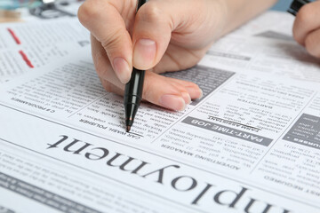 Obraz premium Woman marking advertisement in newspaper, closeup. Job search concept