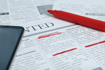 Obraz premium Smartphone and marker on newspaper. Job search concept