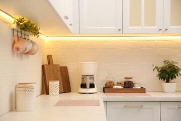 Modern coffeemaker on countertop near brick wall in kitchen