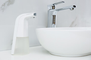 Modern automatic soap dispenser near sink in bathroom, closeup