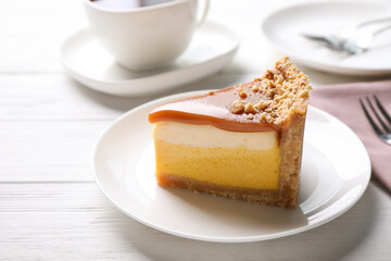 Piece of delicious cake with caramel served on white wooden table