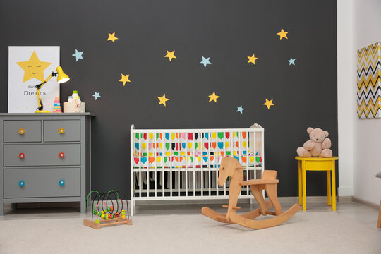 Cute baby room interior with modern crib and rocking horse