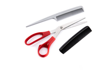 hair cutting tools including red handle scissors and two combs isolated on white