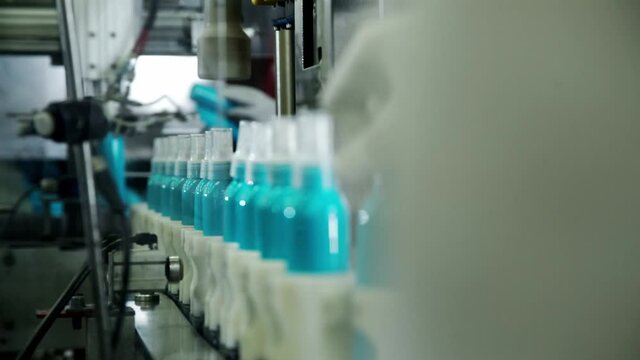 Automated conveyor in cosmetic factory. Automating closing bottle caps