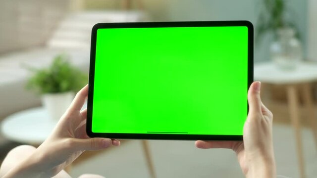 Point of View of Woman Holding and Using Hand Gestures on Green Mock-up Screen Digital Tablet Computer Sitting on a Chair. Girl Buying stuff or Browsing Through the Internet.