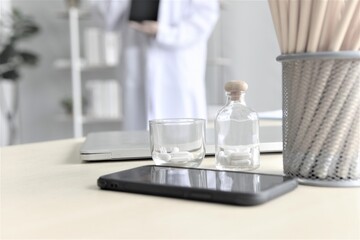 Fototapeta na wymiar glass and bottle of pills on table at hospital