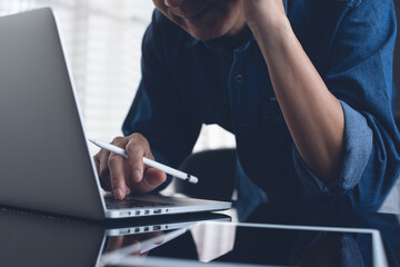 Closeup of asian casual business man working on laptop computer and digital tablet 