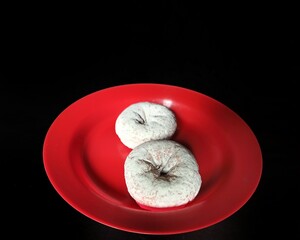 Donuts glazed with sugar in a red plate on a black background. desserts concept