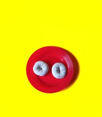 Donuts glazed with sugar in a red plate on a yellow background. desserts concept