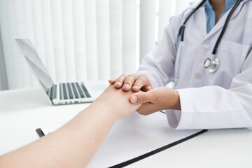 The doctor is holding patient's hand for encouraging patient in the hospital.