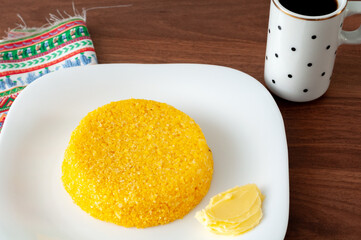 tasteful and colorful brazilian corn couscous served with a cup of coffee on a wooden table
