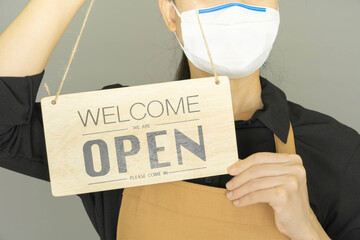 Selective focus small business owner wore medical face mask and holding the sign for the reopening of the place after the quarantine