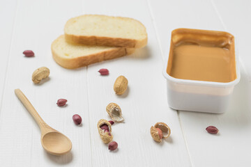 Peanut paste, white bread and peanut fruit on a white table.