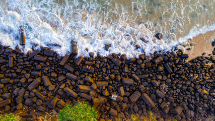 Top down aerial view of person sitting on rocks by the ocean at Burleigh headland, Gold Coast.