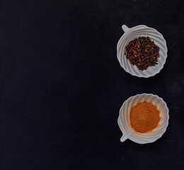 Spices and grains in white cups on a black background. Top view. Turmeric and chili