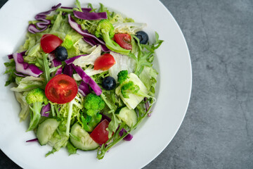 A plate of delicious and healthy green vegetable salad. A plate of delicious and healthy vegetable salad on a gray concrete floor.
