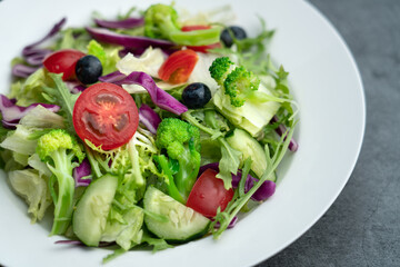 A plate of delicious and healthy green vegetable salad. A plate of delicious and healthy vegetable salad on a gray concrete floor.
