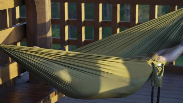 Hiker man relaxing in hammock on viewing tower on summer day, low angle close up shot,  Wigry National Park, Suwalszczyzna, Poland