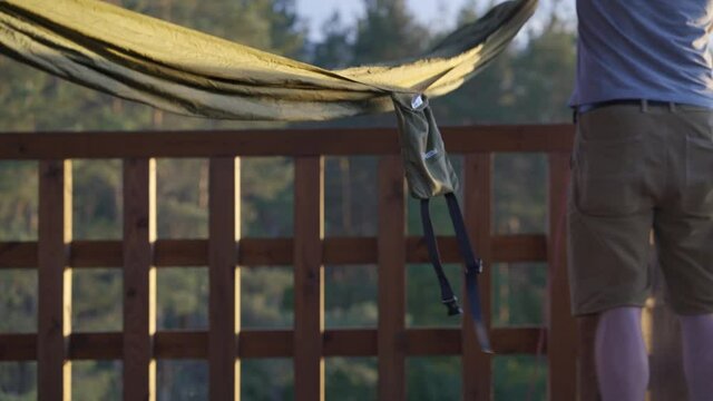 Man setting up hammock on viewing tower of national park during golden hour, low angle shallow focus close up shot, Wigry National Park, Suwalszczyzna, Poland