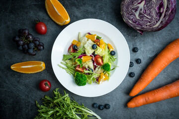 A plate of delicious and healthy green vegetable salad. A plate of delicious and healthy vegetable salad on a gray concrete floor.