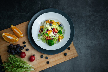 A plate of delicious and healthy green vegetable salad. A plate of delicious and healthy vegetable salad on a gray concrete floor.