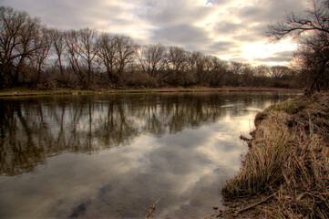 The Grand River lined by leafless willow trees, shot at sunrise in early spring. Shot in Kitchener, Ontario, Canada.