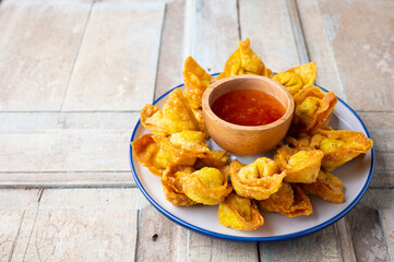 Deep fired Chinese Thai style wonton with minced pork and sweet and sour sauce in ceramic dish.