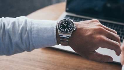 fashionable wearing stylish looking at luxury watch on hand check the time at workplace.concept for managing time organization working,punctuality,appointment