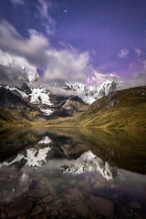 Night photo of lake and mountain with dramatic clouds and purple sky
