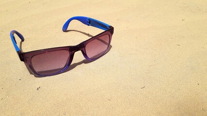 Bluish violet shade with shiny plastic frame on sand in desert in sunlight