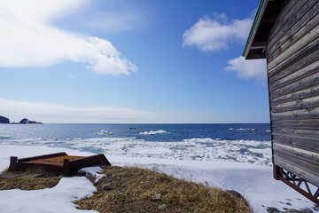 Rustic wood cabin on a snowy beach in Hokkaido with Sea ice on the shoreline. © Dane