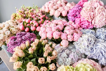 Many different colors on the stand or wooden table in the flower shop. Showcase. Background of mix of flowers. Beautiful flowers for catalog or online store. Floral shop and delivery concept. Top view