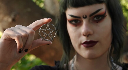 Close up of a silver pentacle held up by a teen Wiccan. Note: Focus is on pentacle.