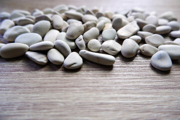 Fototapeta na wymiar White pebbles stone on wood table background＿川石、化粧石、小石