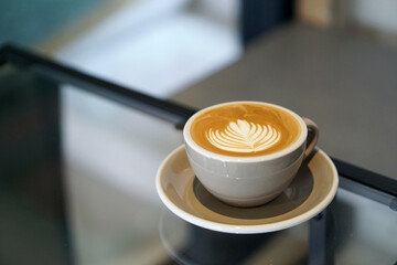 Hot Latte - A cup of coffee with milk and beautiful leaf pattern latte art on wooden table and copy space, Perfect for breakfast time.