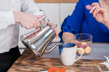 Waitress hands pour coffee to a woman from a teapot into a mug close up