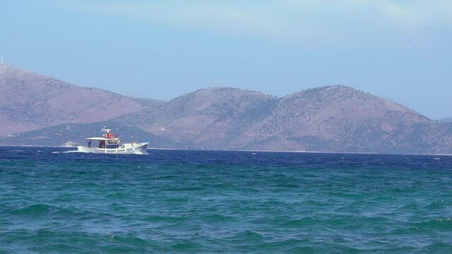 Slow motion of a fishboat set on at aegean sea, with Evia island on there background