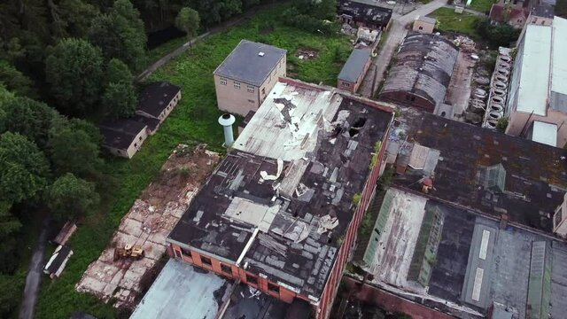 Drone flight over destroyed roof top of old abandoned socialist factory in the woods in Europe