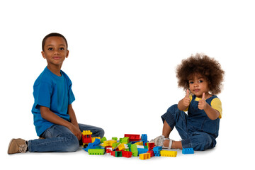 Two little cute african american children playing on the floor with lots of colorful plastic blocks in studio, isolated on white background