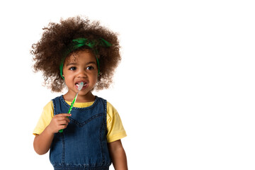 A little cute african american girl brushing her teeth, isolated over white background with copyspace. Healthy teeth concept.